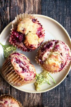 three muffins on a white plate with green garnish and two other muffins