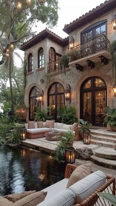 an outdoor living area with couches and tables next to a pool in front of a house