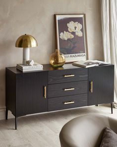 A contemporary dark wood sideboard with vertical fluted details and brass coloured handles. It stands on slender metal legs and showcases a symmetric design with two doors flanking three central drawers. Wall Mounted Sideboard, Black Sideboard Living Room, Sideboards Living Room Inspiration, Black Buffet Sideboard, Kitchen Sitting Room, Sideboard Black, Black Buffet, Contemporary Sideboard, Sideboards Living Room