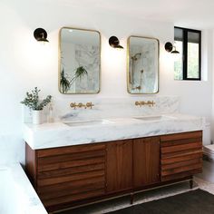 a bathroom with two sinks and mirrors on the wall next to a toilet in it