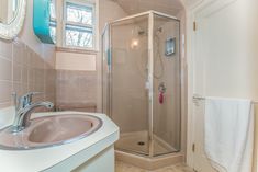 a bathroom with a sink, mirror and shower in it's corner stall area