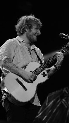 a man holding a guitar while standing next to a microphone