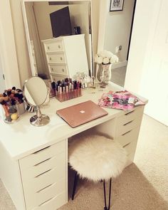 a white desk topped with a laptop computer sitting next to a mirror and vanity area