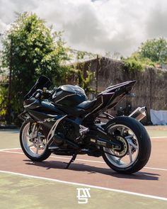 a black motorcycle parked on top of a tennis court