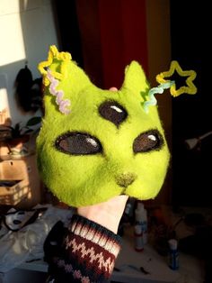 a person wearing a green cat mask with flowers on it's head and eyes