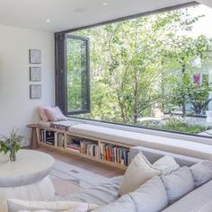 a living room filled with furniture and a large window next to a wall mounted tv