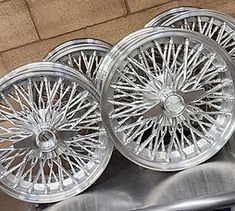 four chrome rims are stacked on top of each other in front of a brick wall