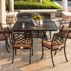 an outdoor table and chairs set up on a patio with sunflowers in the vase