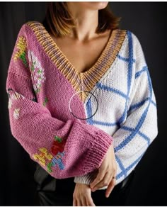 a woman wearing a sweater with flowers on it and her hands in her pockets, standing against a black background