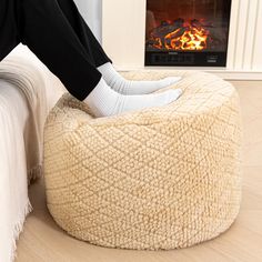 a person sitting on a bean bag chair in front of a fire place with their feet up