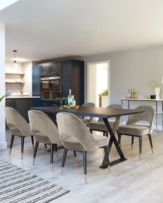 a dining room table with six chairs and a rug on the floor in front of it