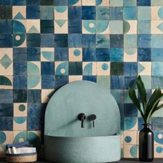 a bathroom with blue and green tiles on the wall, sink and vases next to it