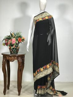 A Marvellous Embroidered Kashmiri Saree which you can wear at any party or a wedding.- - - - - - - - - - - - - - - - - - - - Product Details- Condition: Brand New (made to order)- Style: Sari Dress- Embroidery: Kashmiri Aari & Tilla Fusion Work- Base Colour: Black- Embroidery Colour: Multi-Colour- Care Instructions: Dry Clean OnlyF A B R I CSaree: Viscose GeorgetteBlouse: Indian CrepeF I N I S H- UnstitchedYou can get it stitched locally.- StitchedWant your blouse ready to wear, let us know Wedding Black Pre-draped Saree With Intricate Embroidery, Traditional Floor-length Georgette Pre-draped Saree, Black Embroidered Pre-draped Saree For Navratri, Traditional Black Pre-draped Saree, Festive Black Embroidered Pre-draped Saree, Bollywood Floor-length Embroidered Fabric For Traditional Ceremonies, Black Pre-draped Saree With Resham Embroidery For Eid, Eid Black Pre-draped Saree With Resham Embroidery, Floor-length Georgette Dupatta For Traditional Ceremonies