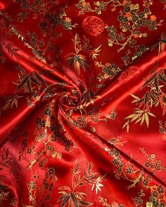 a red fabric with gold and black flowers on it