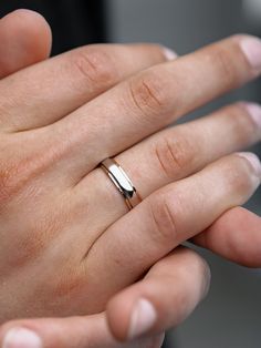 a person's hand with a wedding ring on their finger, holding something in the other hand