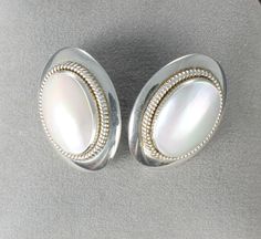 Beautiful Waldeck Johnson sterling silver stud earrings. They are oval in shape and feature a mother of pearl cabochon framed with silver rope. Length:  1  1/8 inches Width:    3/4 inches In excellent condition. Silver Oval Cabochon Earrings, Formal Silver Oval Cabochon Earrings, Vintage White Oval Earrings, White Oval Earrings With Polished Finish, Spartanburg Sc, Oval Stud Earrings, Sterling Silver Stud Earrings, Silver Stud Earrings, Sterling Silver Studs