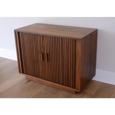 a wooden cabinet sitting on top of a hard wood floor next to a white wall