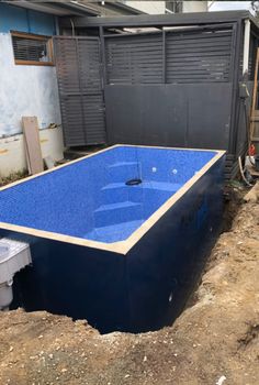 a large blue swimming pool in the middle of an unfinished yard with dirt and debris around it