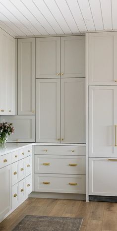 an empty kitchen with white cabinets and gold hardware on the doors, drawers and cupboards