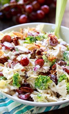 a salad with broccoli, grapes and nuts in a bowl on a table