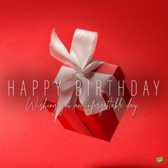 a red gift box with a white bow on it and the words happy birthday written below