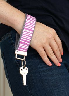 a person wearing a purple and white striped wristband with a silver key on it