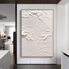 a large white painting hanging on the side of a wall next to a dining room table