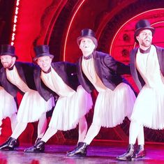 a group of men in tuxedos are performing on stage