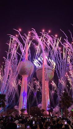 fireworks are lit up in the night sky behind two tall buildings with spires on them