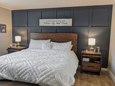 a bed with white sheets and pillows in a bedroom next to two nightstands on either side of the bed