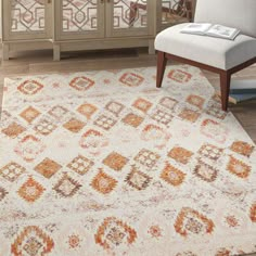 a white rug with an orange and brown design on it in front of a cabinet