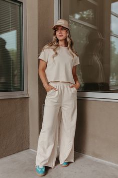 Look super cute and feel comfortable all day in THE SARA SET IN CREAM! This travel outfit includes a raw hem, cropped short sleeve sweater and wide leg pants with an elastic waist. Perfect for wearing all day, this set is both stylish and comfortable. Paired with THE HOWDY DARLIN' TRUCKER HAT IN BEIGE & THE FIERCE SNEAKERS IN GREEN Sold as a set. Top: Short sleeve Round neck Raw hem Slightly cropped Loose fit 80% polyester, 20% spandex Bottom: Wide leg Pockets Relaxed fit Elastic waistband Raw h Cream Loose Pants Outfit, Casual Cotton Wide Leg Sets, Versatile Cropped Bottoms For Loungewear, Beige Casual Loungewear Sets, Casual Beige Loungewear Sets, Casual Beige Lounge Sets, Casual Cotton Sets With Elastic Waistband, Casual Wide Leg Sets For Day Out, Cotton Sets With Elastic Waistband And Short Sleeves