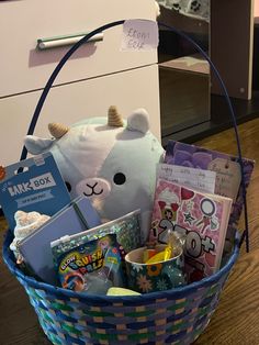 a basket filled with books and toys on top of a wooden floor