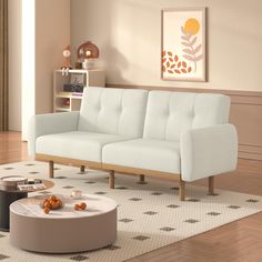 a white couch sitting on top of a wooden floor next to a table and chair