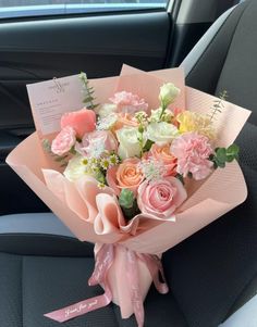 a bouquet of flowers sitting in the back seat of a car with a note attached to it