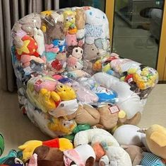 a child's chair with stuffed animals all over it sitting on the floor next to other toys