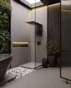 a bathroom with a large shower head next to a bathtub and plants on the floor