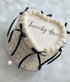 a heart shaped cake with the words twenty three written on it and tied in black ribbon