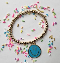 Smiley face charm bracelet. Playful Hypoallergenic Bracelets For Gifts, Fun Blue Beaded Bracelets For Gifts, Personalized Fun Gold Bracelets, Fun Gold Jewelry For Birthday, Cute Blue Charm Bracelet For Gift, Fun Blue Bracelets For Gifts, Playful Nickel-free Bracelets As Gifts, Cute Blue Bracelet For Birthday, Playful Nickel-free Bracelet As A Gift