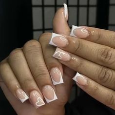 two hands with white and pink nail polish holding each other's fingers in the shape of hearts