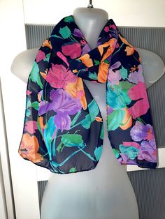 This is a beautiful multicolored scarf featuring exotic flowers on a black background. The scarf combines the orange, green, teal, pink and purple colors. The scarf does not have a tag to know the origin of the scarf but it is in mint condition. It will surely make a beautiful gift too. The scarf is nylon polyester. The scarf comes in a gift wrap and with a 'Thank you' card. For more scarves in my store visit: https://www.etsy.com/ca/shop/NostalgicByLiliya?ref=search_shop_redirect§ion_id=2503114 Casual Multicolor Silk Scarf For The Beach, Multicolor Floral Print Scarf, One Size, Black Bohemian Scarf With Floral Print, Black Bohemian Scarves With Floral Print, One Size Multicolor Floral Print Scarf, Multicolor Floral Print Beach Scarf, Multicolor Floral Print Scarf For Beach, Blue Floral Print Scarf For Beach, Multicolor Floral Silk Scarf For Beach