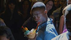 a young man eating an ice cream sundae in front of a group of people