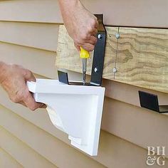 a man is using a drill to fix a house siding gap on the side of a house