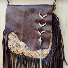 Channel the spirit of the Southwest with this boho handbag from Jewelry Junkie! Featuring a bold, Chateau print, this crossbody bag is sure to leave an impression. Made from genuine leather Fully lined Zipper closure Comes with a matching crossbody leather strap 36" long Measures 10” x 9” with a 10” leather fringe Genuine leather flap with raw cowhide edge Suede Lacing on the front of the flap Handmade and sourced in Texas, so no two bags are ever identical Embossed pattern evokes images of the Bohemian Crossbody Hobo Bag, Bohemian Hobo Crossbody Bag, Leather Bohemian Pouch Bag, Bohemian Leather Pouch Bag, Bohemian Leather Shoulder Bag With Leather Handles, Bohemian Leather Bags With Leather Handles, Brown Festival Bag With Removable Pouch, Bohemian Leather Pouch Hobo Bag, Bohemian Leather Hobo Pouch Bag