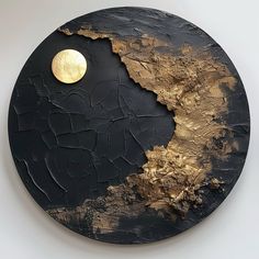 a black and gold plate with a half - moon on the top, in front of a white wall