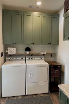 a washer and dryer in a small room with green cabinets on the walls