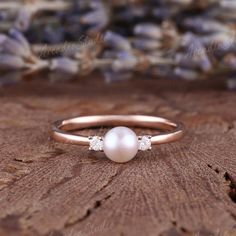 a pearl and diamond ring sitting on top of a piece of wood