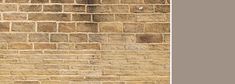 an old brick wall with a clock on it's side and a sign in the foreground