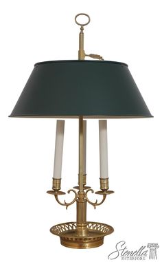 a brass table lamp with two white candles on it and a green lampshade