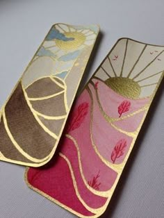 two bookmarks with designs on them sitting next to each other in front of a gray background